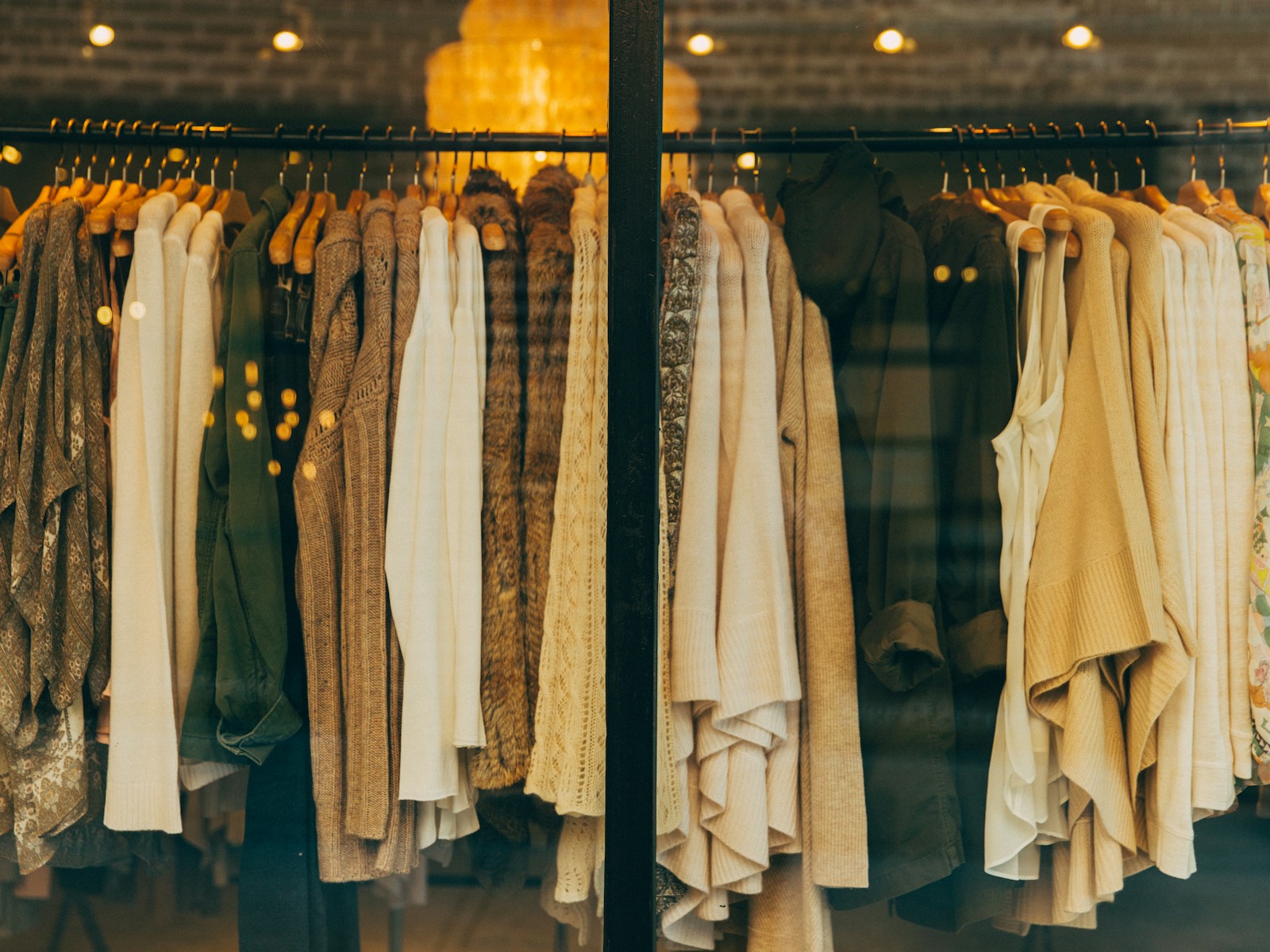 Boutique window filled with cream and camel knitwear on wooden hangers